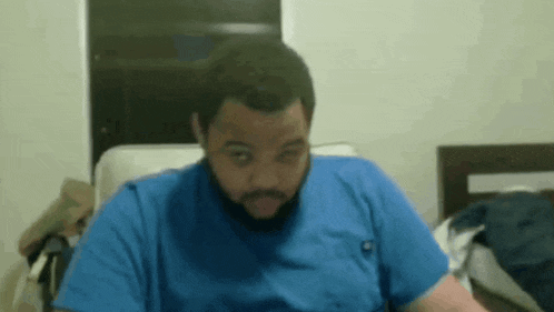 a man in a blue shirt is sitting in a chair making a funny face