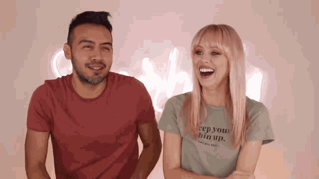 a man and a woman are laughing and the woman is wearing a t-shirt that says keep your chin up