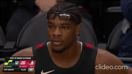 a basketball player adjusts his glasses in front of a scoreboard that says 12 20