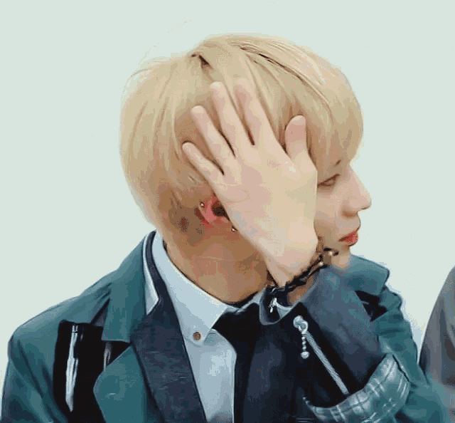 a man covering his face with his hand while wearing a green jacket