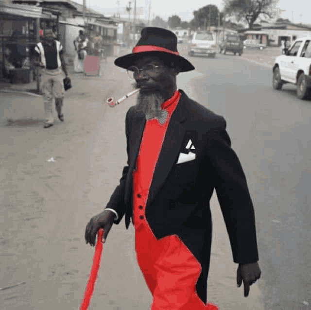 a man in a black suit and red pants is smoking a pipe
