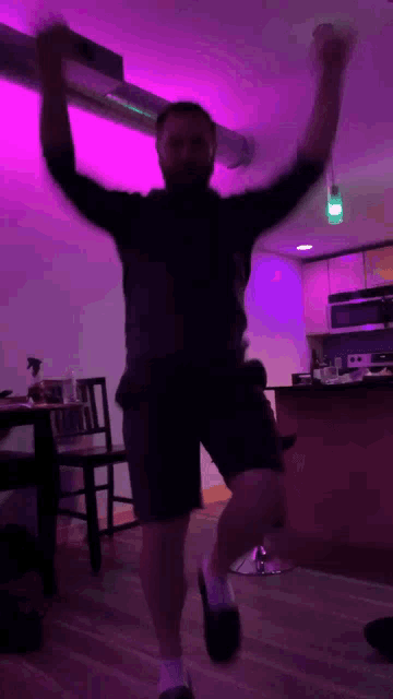 a man is dancing in a room with purple lights