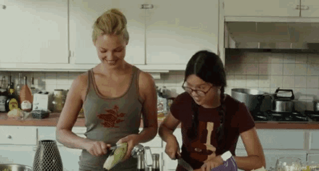 two women are preparing food in a kitchen and one of them is wearing a shirt that says " i love you "