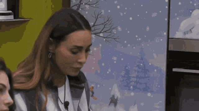 a woman is standing in front of a painting of a snowy scene .