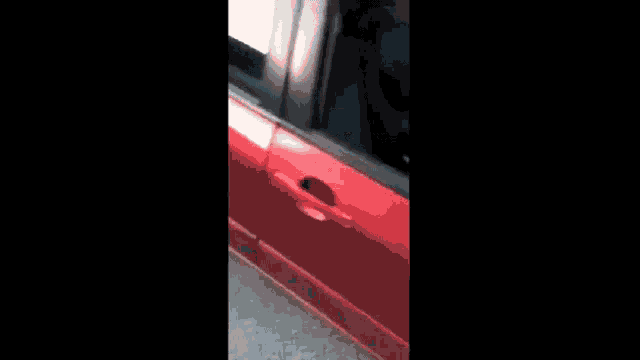 a man is sitting in the passenger seat of a red car .