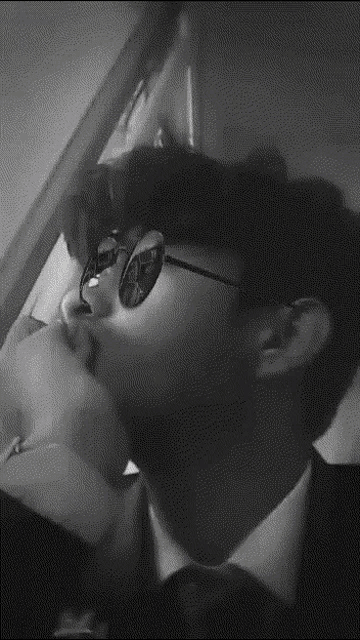 a man wearing sunglasses and a suit is kissing another man