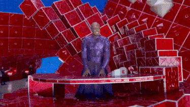 a man in a purple suit is standing in front of a red cube display