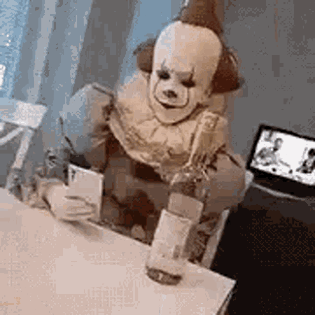 a person dressed as a clown is sitting at a table with a bottle of alcohol .