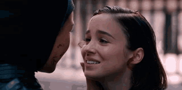 a woman with a tattoo on her face is touching another woman 's face and smiling