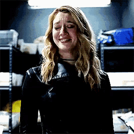 a woman wearing a black leather jacket is crying with her eyes closed
