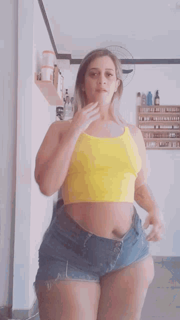 a woman in a yellow top and blue skirt is dancing in a room