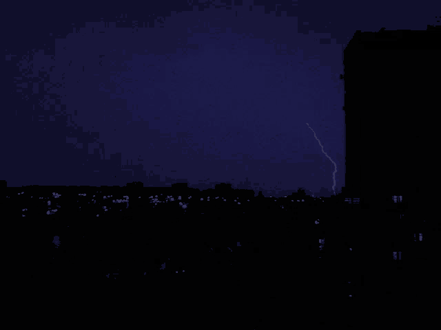 a lightning bolt strikes in the night sky over a city