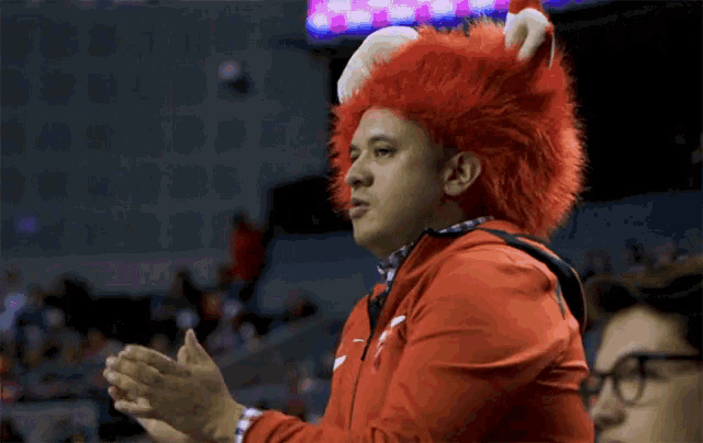 a man wearing a red bunny costume applauds during a game