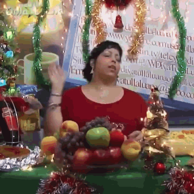 a woman in a red shirt stands in front of a table with fruit and a sign that says ' coca-cola '