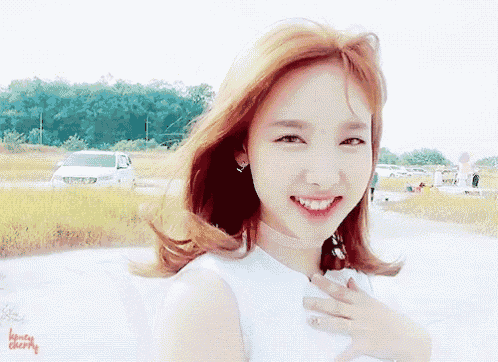 a woman with red hair is smiling and looking at the camera while wearing a white shirt .