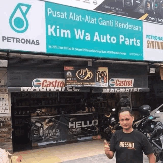a man giving a thumbs up in front of a petronas sign