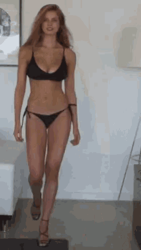 a woman in a bikini is walking through a living room .