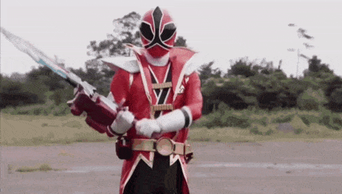 a red power ranger is holding a large sword .