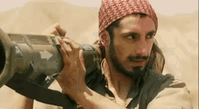 a man with a beard is holding a cannon in his hands .