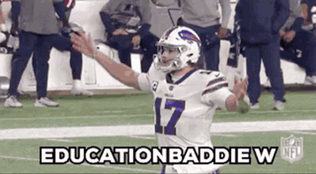 a football player in a buffalo bills uniform is standing on a field with his arms in the air .
