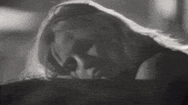 a black and white photo of a woman with long hair laying down .