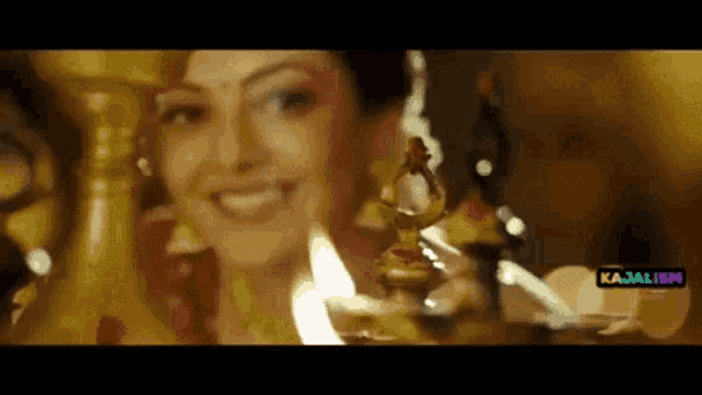 a woman is smiling in front of a candle and a statue .
