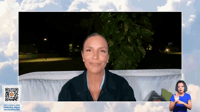 a woman is smiling in front of a screen that says " parada pela solidariedade "