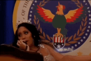 a woman with a crown on her head is sitting in front of a seal with a rooster on it .