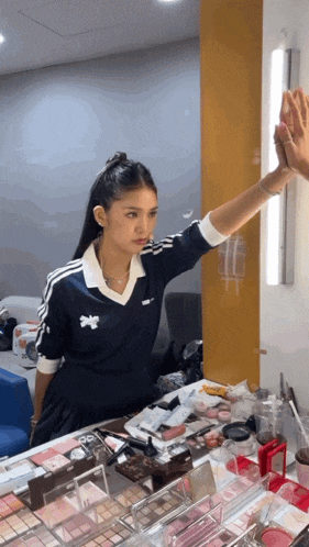 a woman in a blue adidas shirt is looking at herself in the mirror