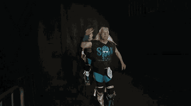 a man with long white hair is wearing a black shirt with a skull on it and is running in the dark .