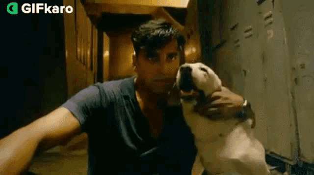 a man is holding a dog in his arms in a hallway .