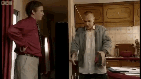 two men are standing next to each other in a kitchen talking .