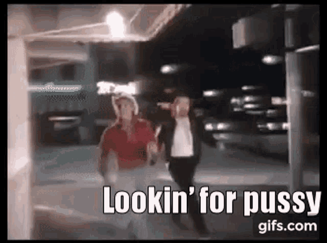 a couple of people walking down a street at night with the words lookin ' for pussy written on the bottom .