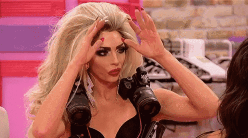 a woman in a wig is holding a camera in her hand and adjusting her hair .