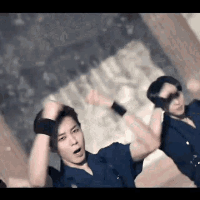 a man in a police uniform is dancing with his hands in the air while another man looks on .