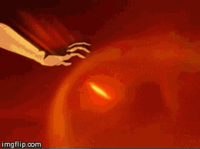 a person 's hand is reaching out towards a fireball in the air .