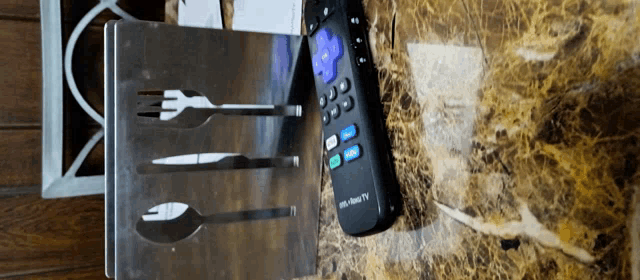 a roku tv remote sits on a marble counter top