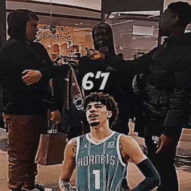 a man wearing a hornets jersey stands in front of a group of men