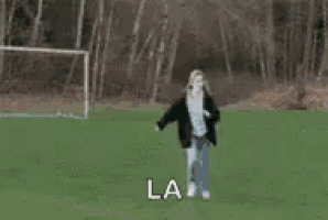 a woman is running away from a horse on a field .