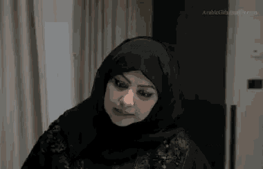 a woman wearing a black hijab is sitting at a table .