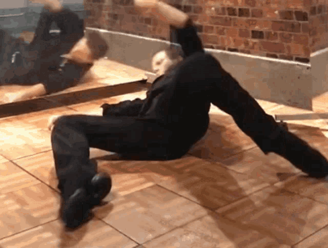 a person laying on their back on a tiled floor in front of a mirror