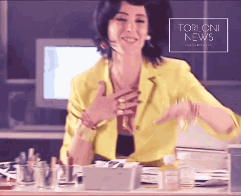 a woman in a yellow jacket is smiling in front of a torloni news advertisement