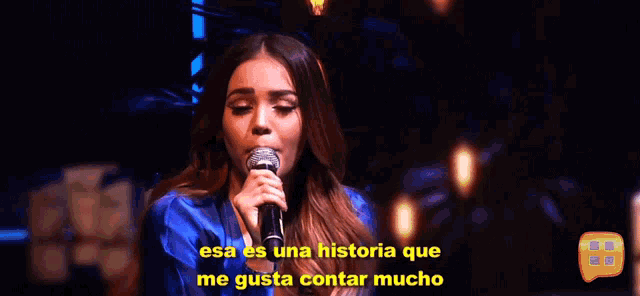 a woman singing into a microphone with the words " esa es una historia que me gusta contar mucho " next to her