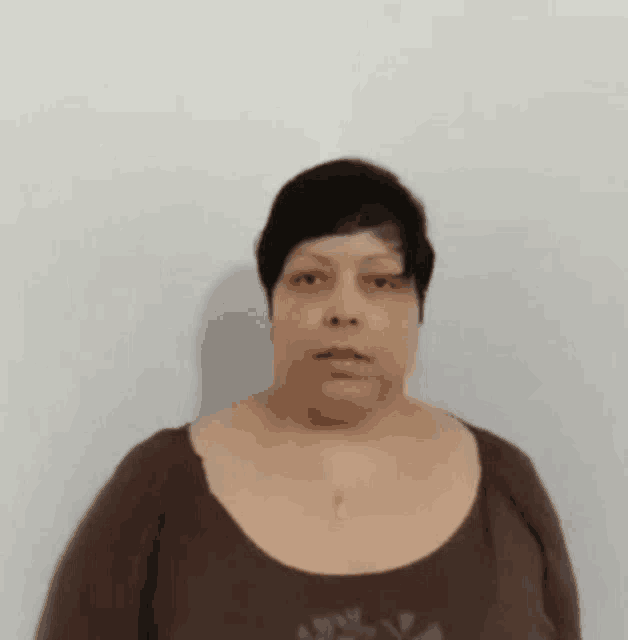a woman with short hair is standing in front of a white wall .