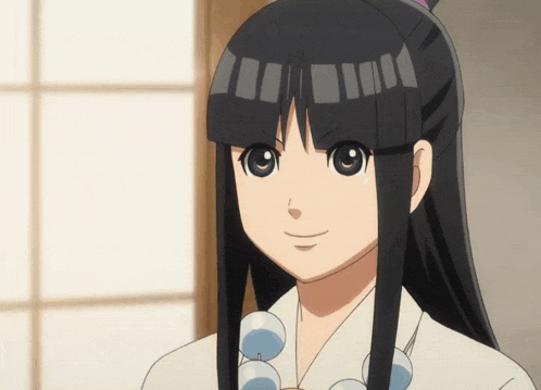 a girl with long black hair is wearing a white shirt and blue beads around her neck