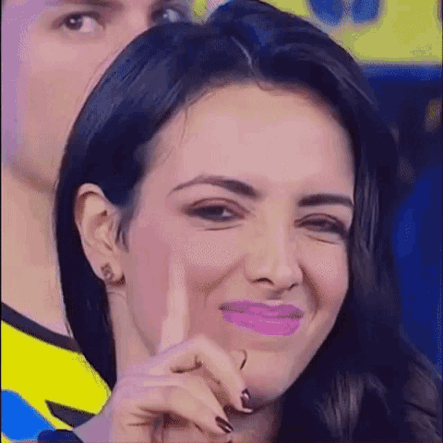 a close up of a woman making a funny face with her finger on her face .