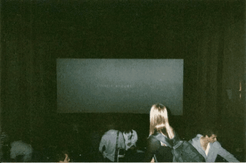 a woman stands in front of a screen with a picture of two dancers on it