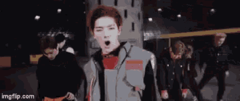 a man with red hair is standing in front of a group of men .