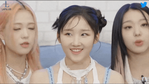 three girls are standing next to each other and one of them is wearing a necklace with the word love on it