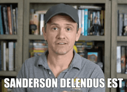 a man wearing a hat stands in front of a bookshelf with the words sanderson delendus est below him